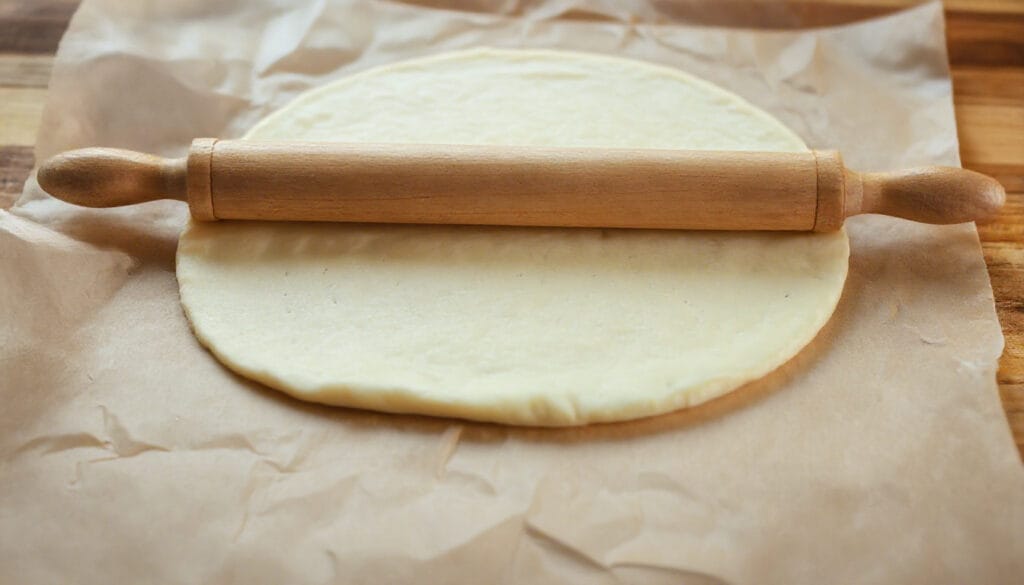 Rolling out low carb tortilla chip dough between parchment paper.