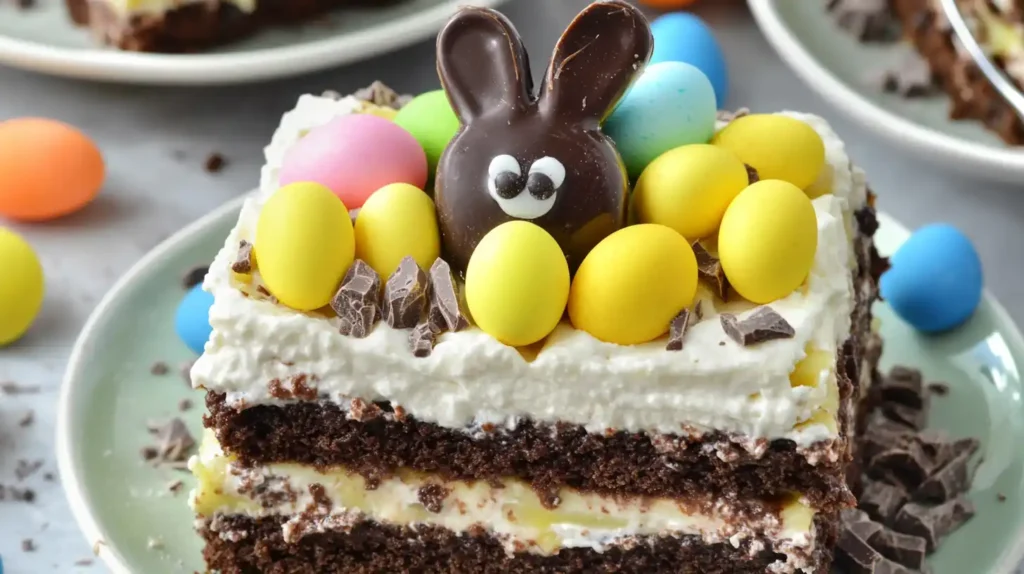 A slice of layered Easter Chocolate Lasagna decorated with a chocolate bunny, yellow mini eggs, and chocolate chunks on a green plate.